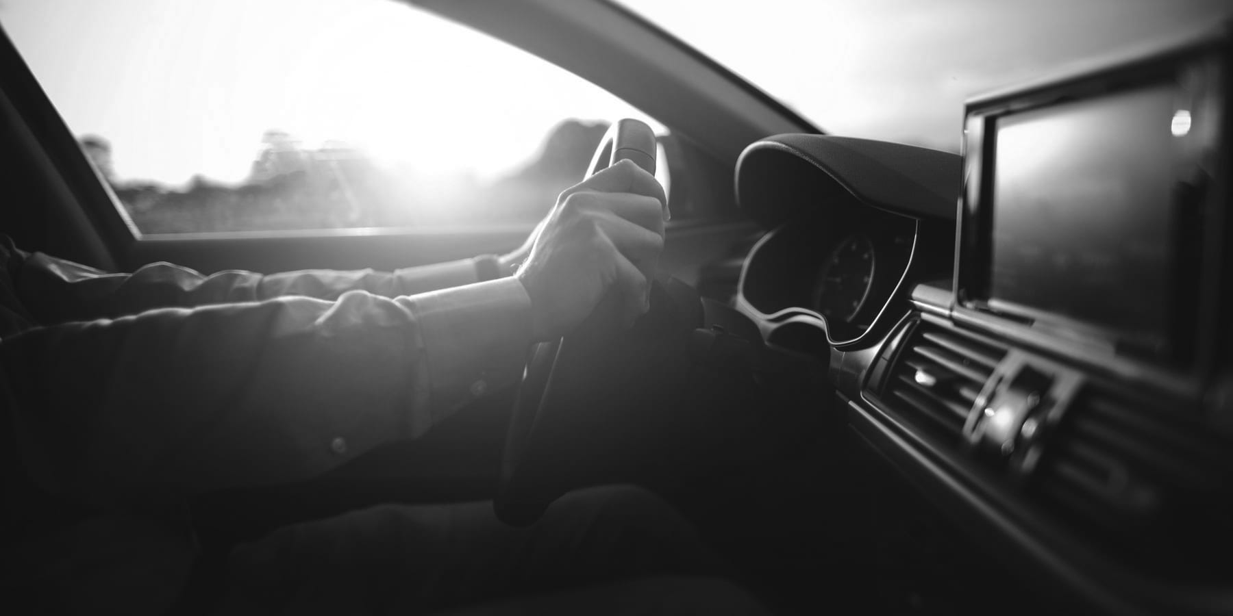 person with their hands on the wheel of a car