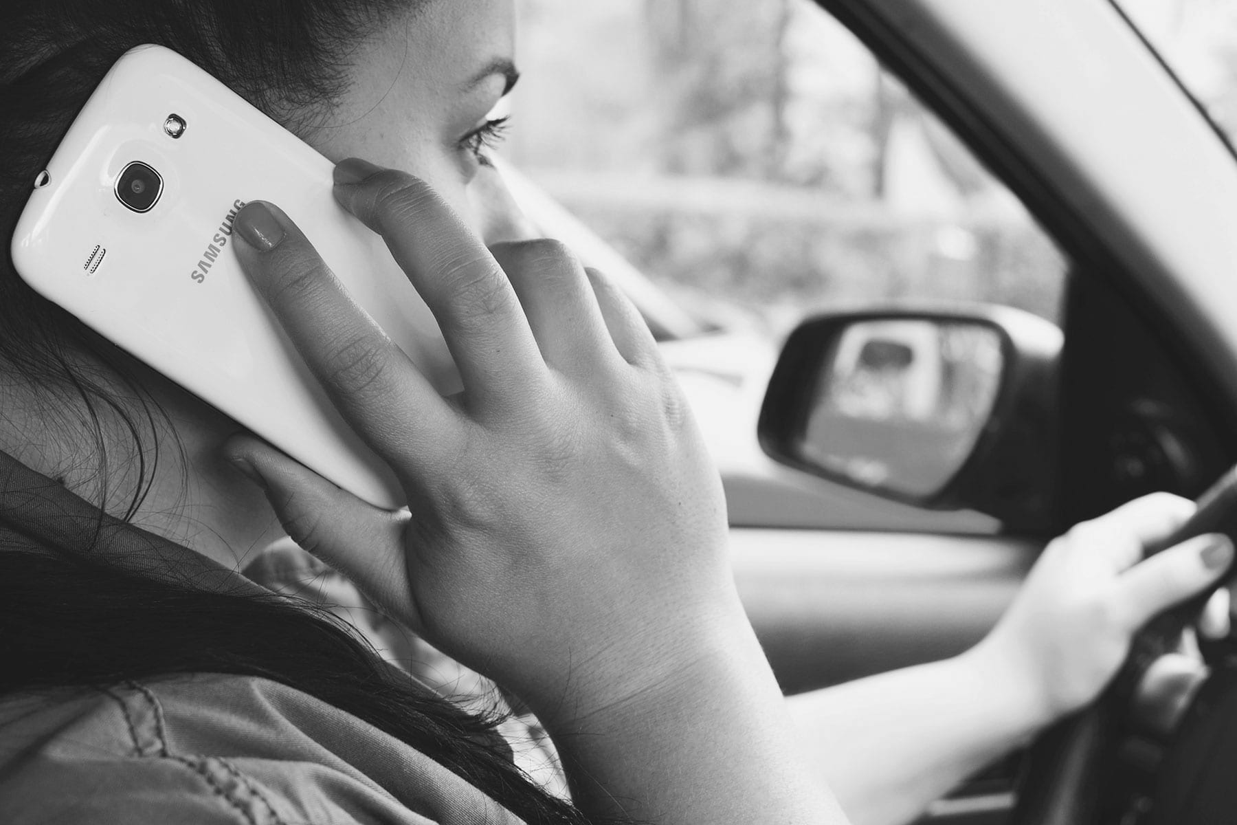 a women using a mobile phone whilst driving a car