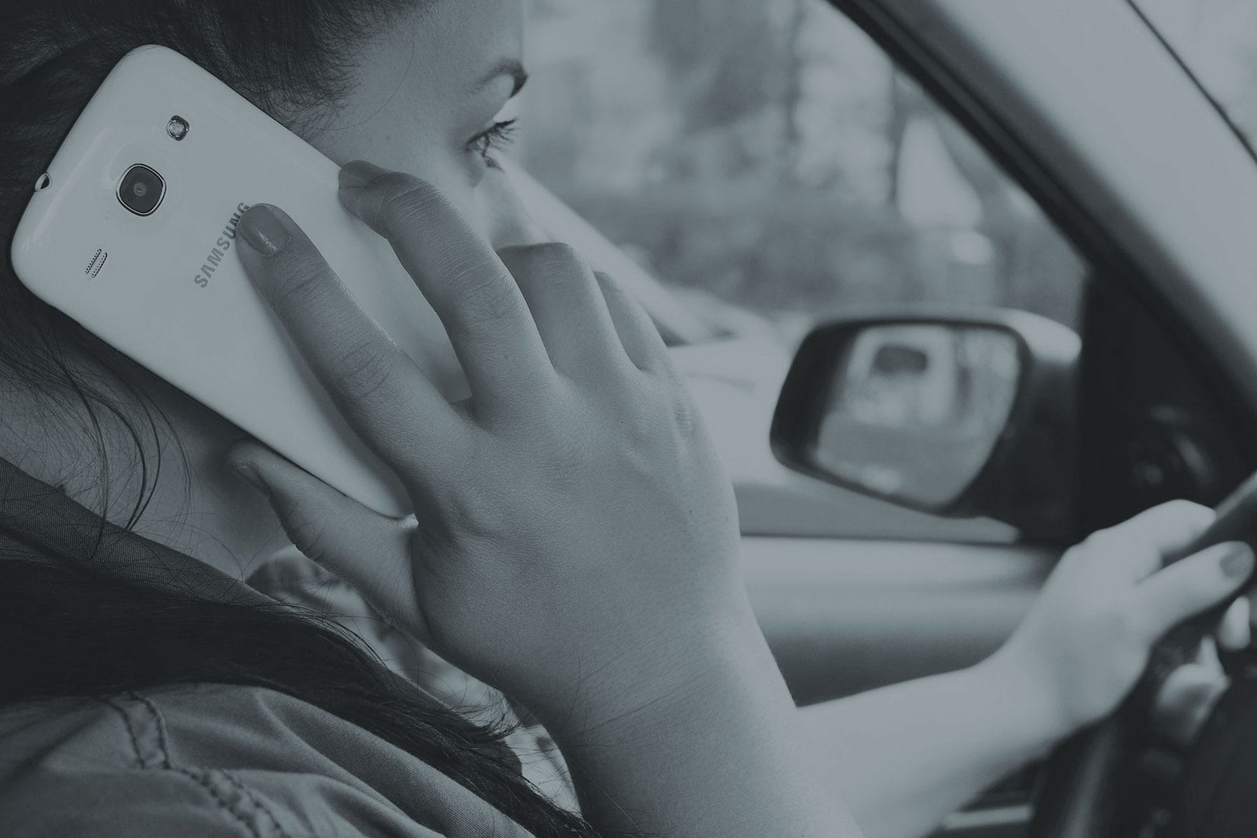 a women using a mobile phone whilst driving a car