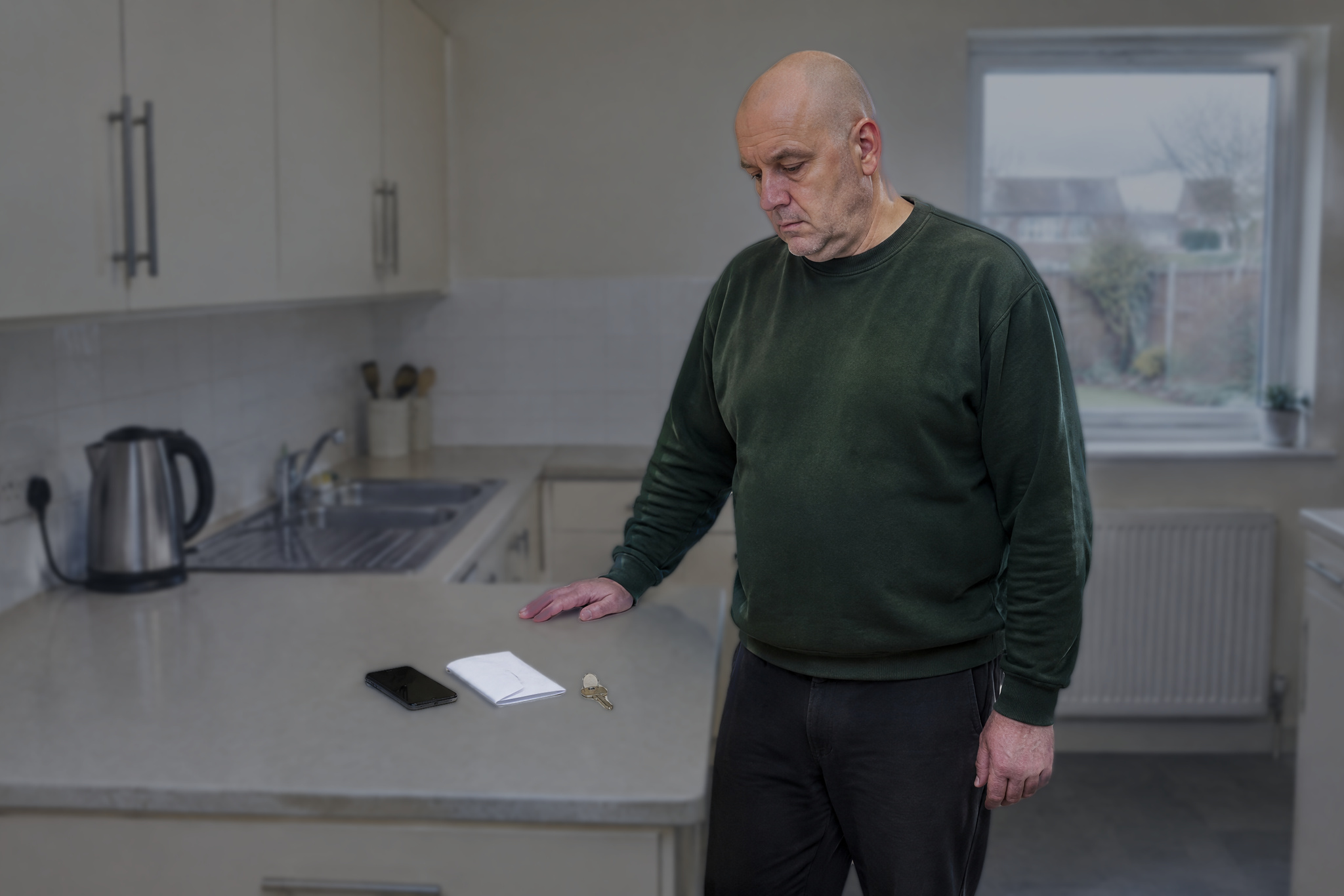 Man standing looking at a phone and letter after domestic abuse charges