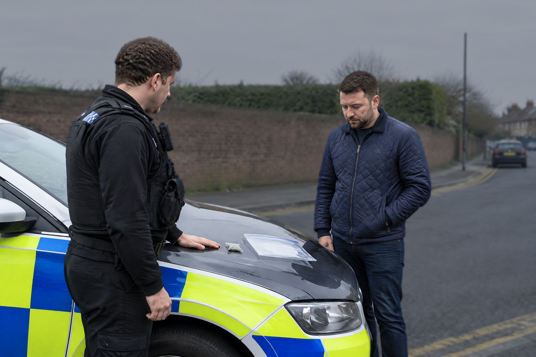 Officer questioning a man beside a car for drug possession