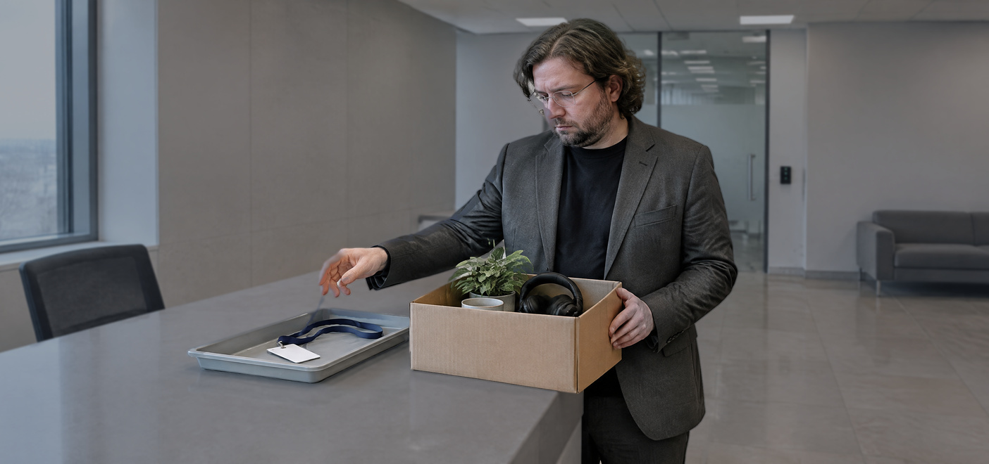 Man holding a box of belongings returning his office pass after an insider dealing investigation