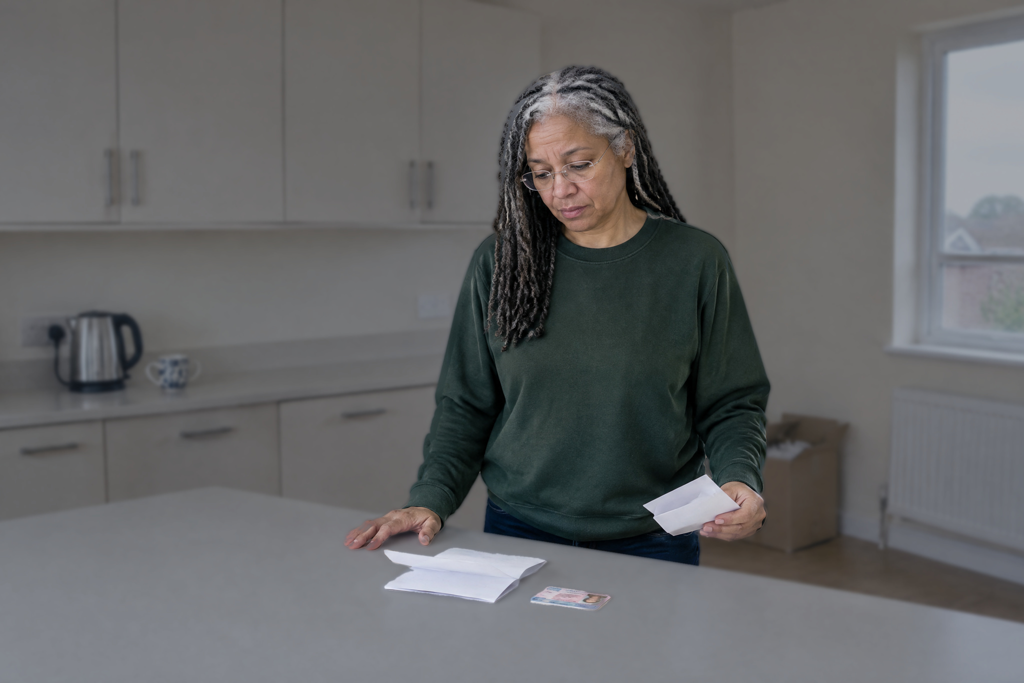 Woman in kitchen reading a DVLA letter beside her driving licence, considering whether to reopen old conviction