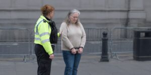 Police officer holding handcuffed woman Arrested at a protest