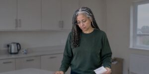 Woman in kitchen reading a DVLA letter beside her driving licence, considering whether to reopen old conviction
