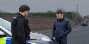 Officer questioning a man beside a car for drug possession